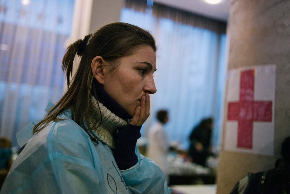 Entsetzen spiegelt sich im Gesicht dieser freiwilligen Helferin einer provisorischen Krankenstation in Kiew wider / Jacob Balzani Lööv, n-ost